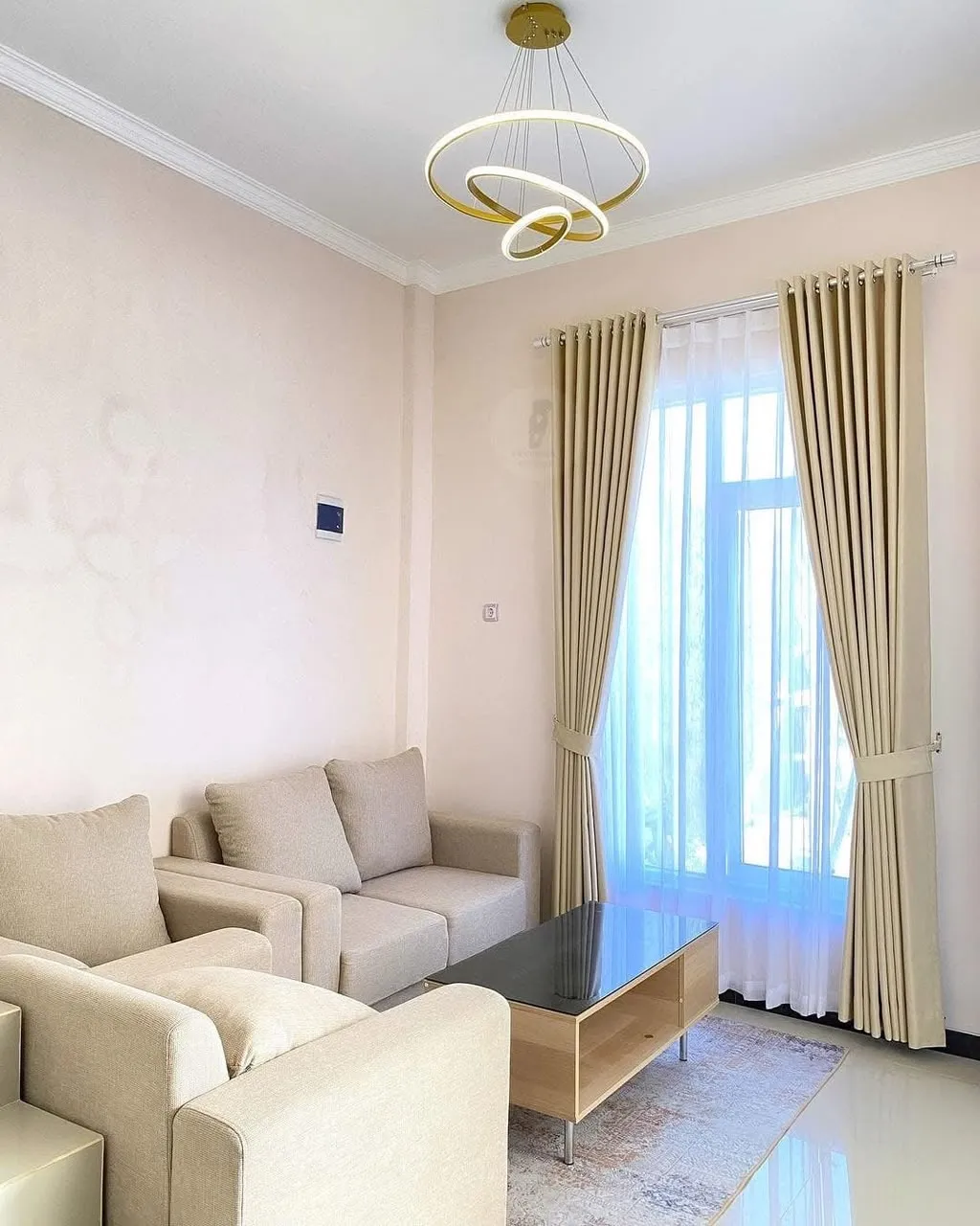 Gorden minimalis krem terang dengan vitrase putih dan sofa senada di ruang tamu modern