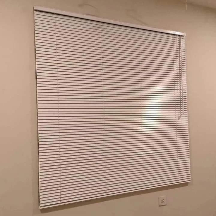 Horizontal blinds putih minimalis yang terpasang rapi pada dinding krem