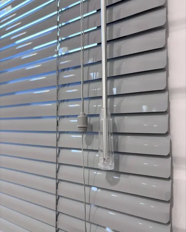 Detail bilah horizontal blinds abu-abu beserta stik pemutar akrilik pengatur cahaya
